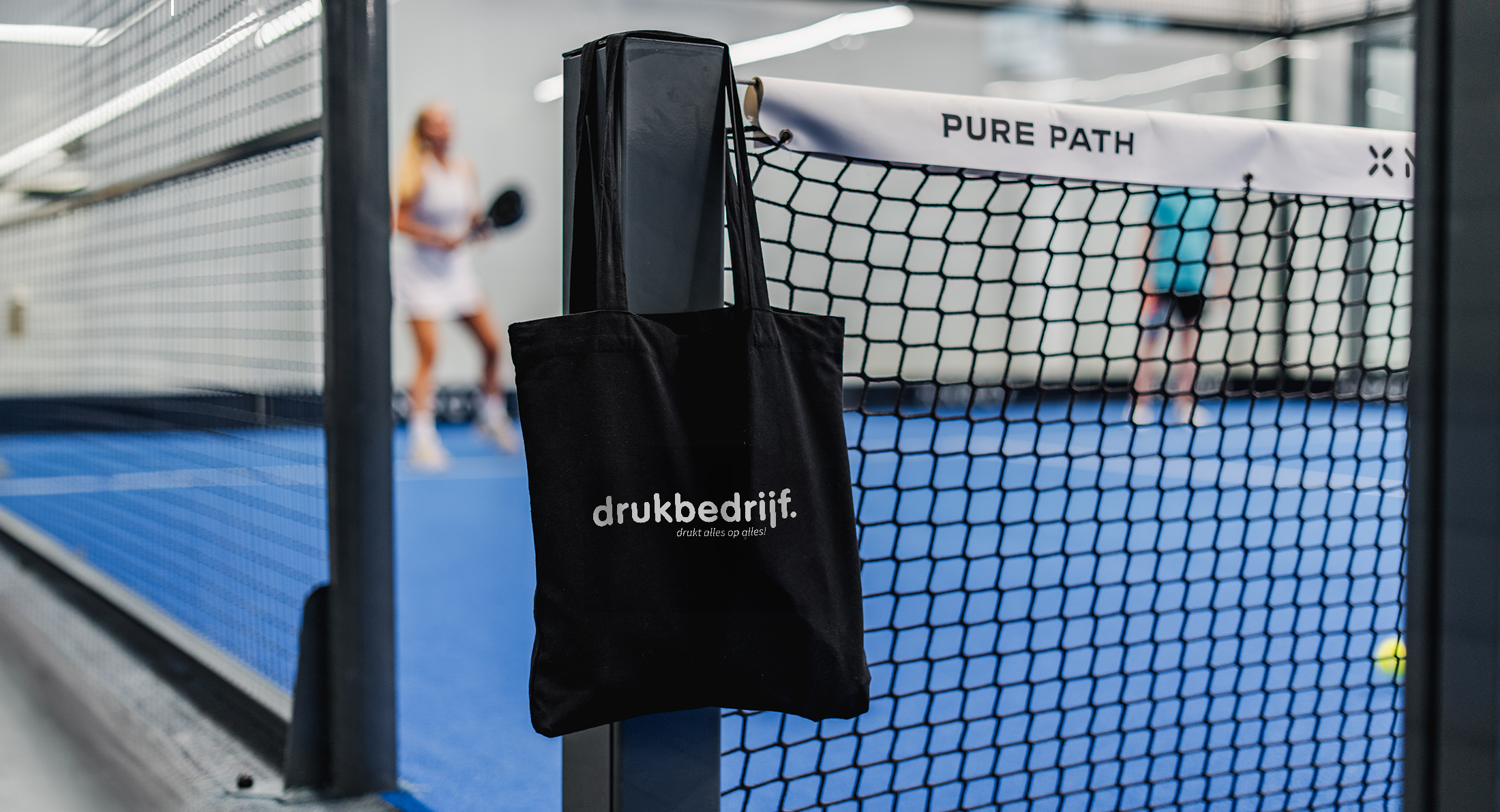 bedrukte canvas tas hangend aan padelnet
